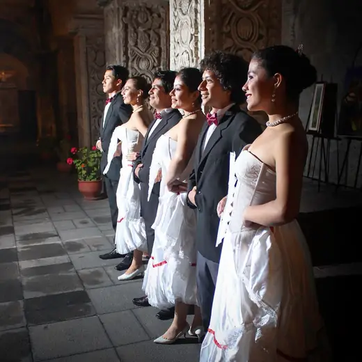 Bailarines con vestuario blanco y negro de pie en una galería de piedra