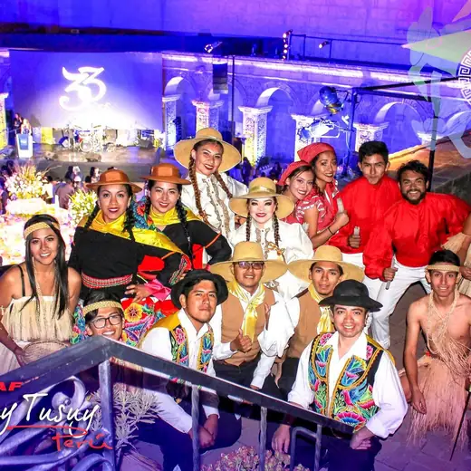 Elenco CIDAF Waylluy Tusuy con vestuario típico posando sobre un escenario iluminado