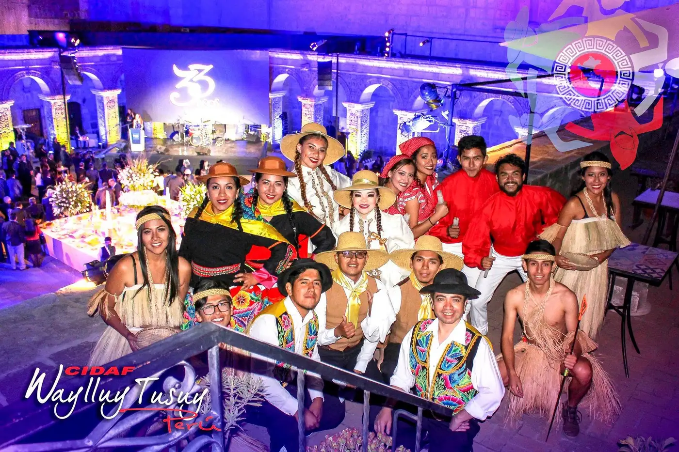 Elenco CIDAF Waylluy Tusuy con vestuario típico posando sobre un escenario iluminado
