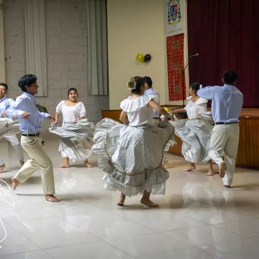 Bailarines de marinera con pañuelo en un salón con público