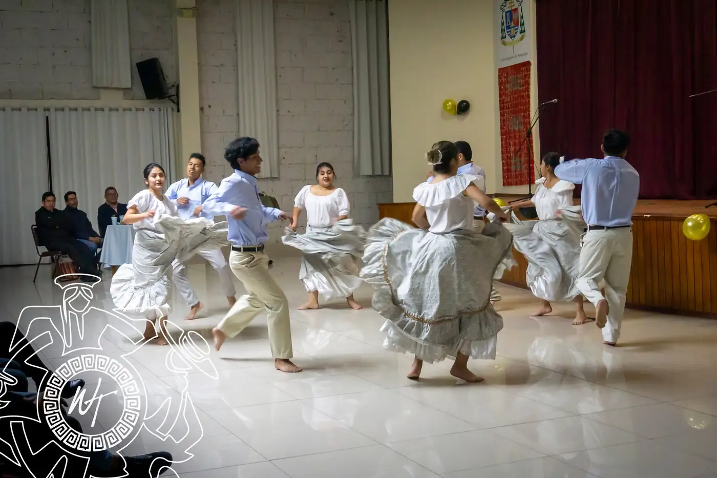 Bailarines de marinera con pañuelo en un salón con público