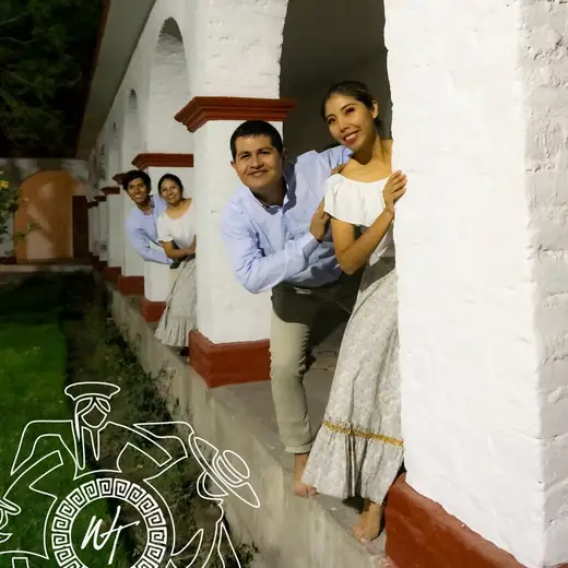 Pareja de bailarines asomada entre los arcos blancos de un claustro