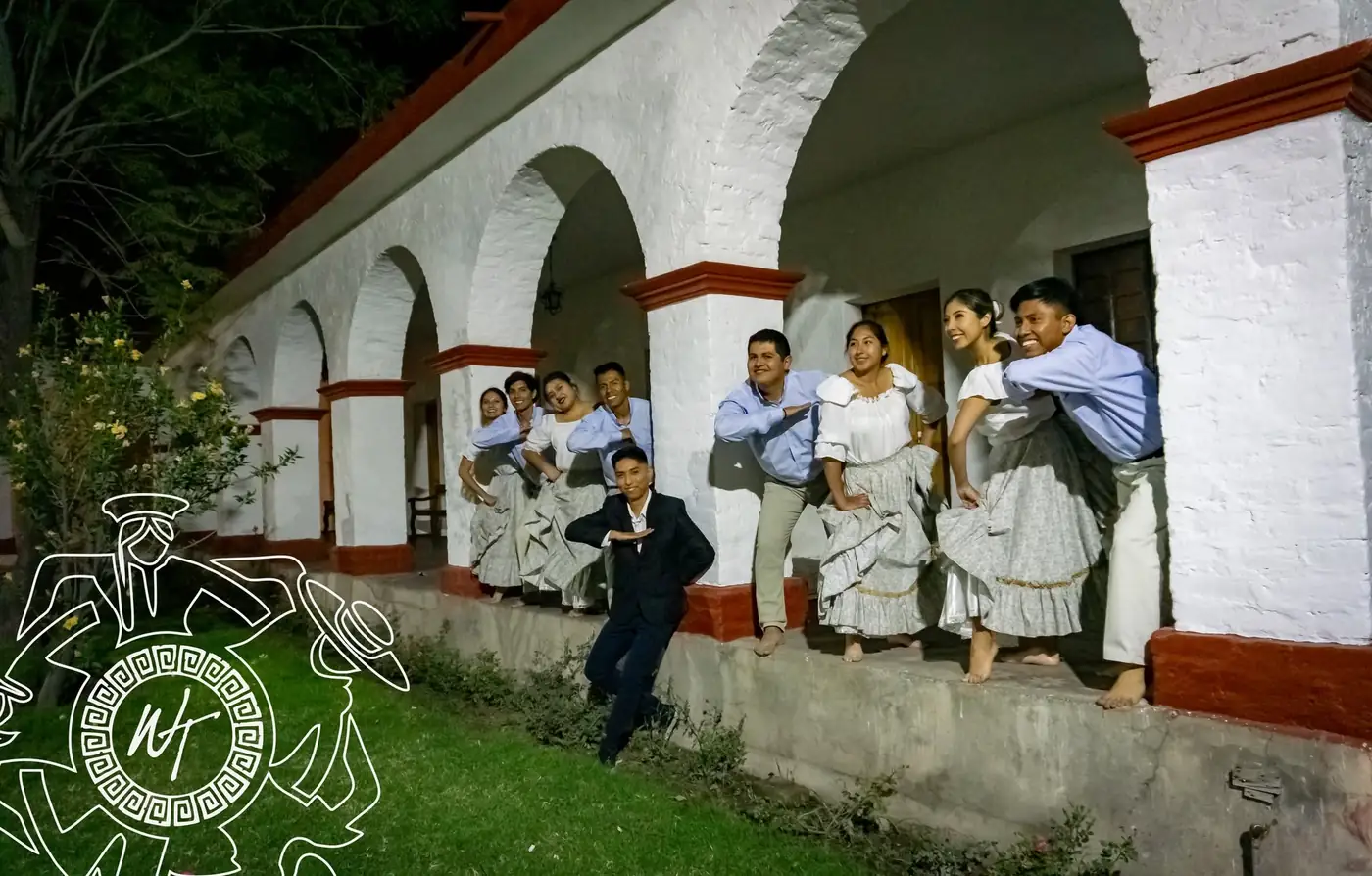 Elenco con vestuario tradicional a lo largo de los arcos blancos de un claustro