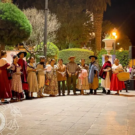 Elenco con vestuarios variados posando en una plaza de noche