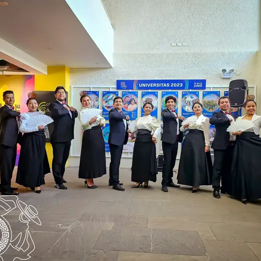 Elenco con vestuario negro posando en el atrio de un edificio moderno