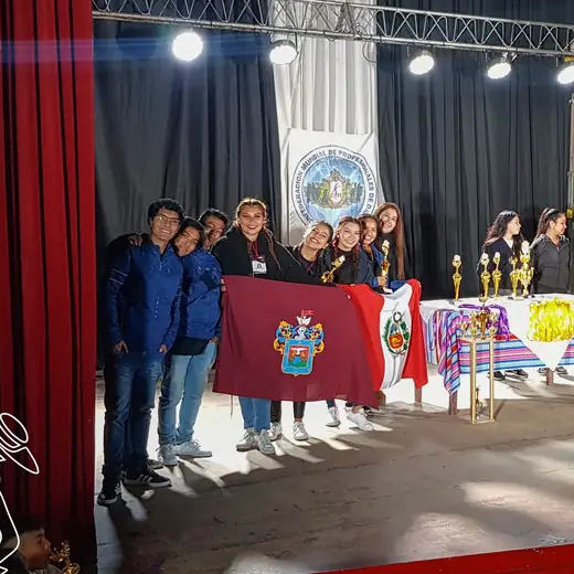 Participantes sobre un escenario con banderas y trofeos