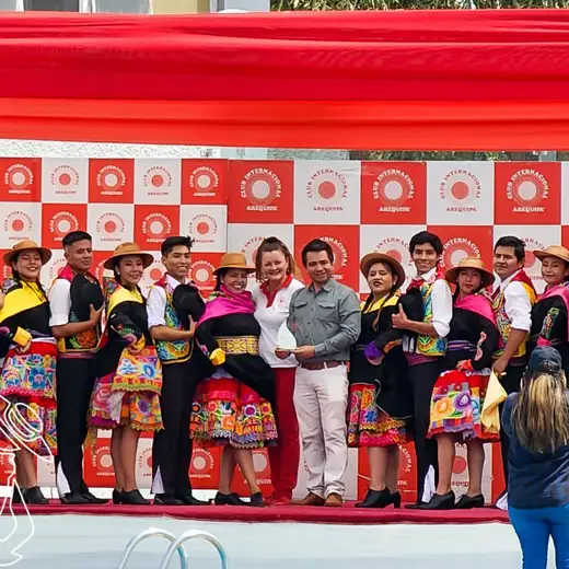 Elenco y autoridades sobre un escenario con fondo rojo