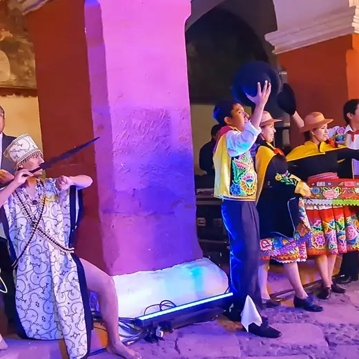 Bailarines con vestuario colorido en un claustro de arcos