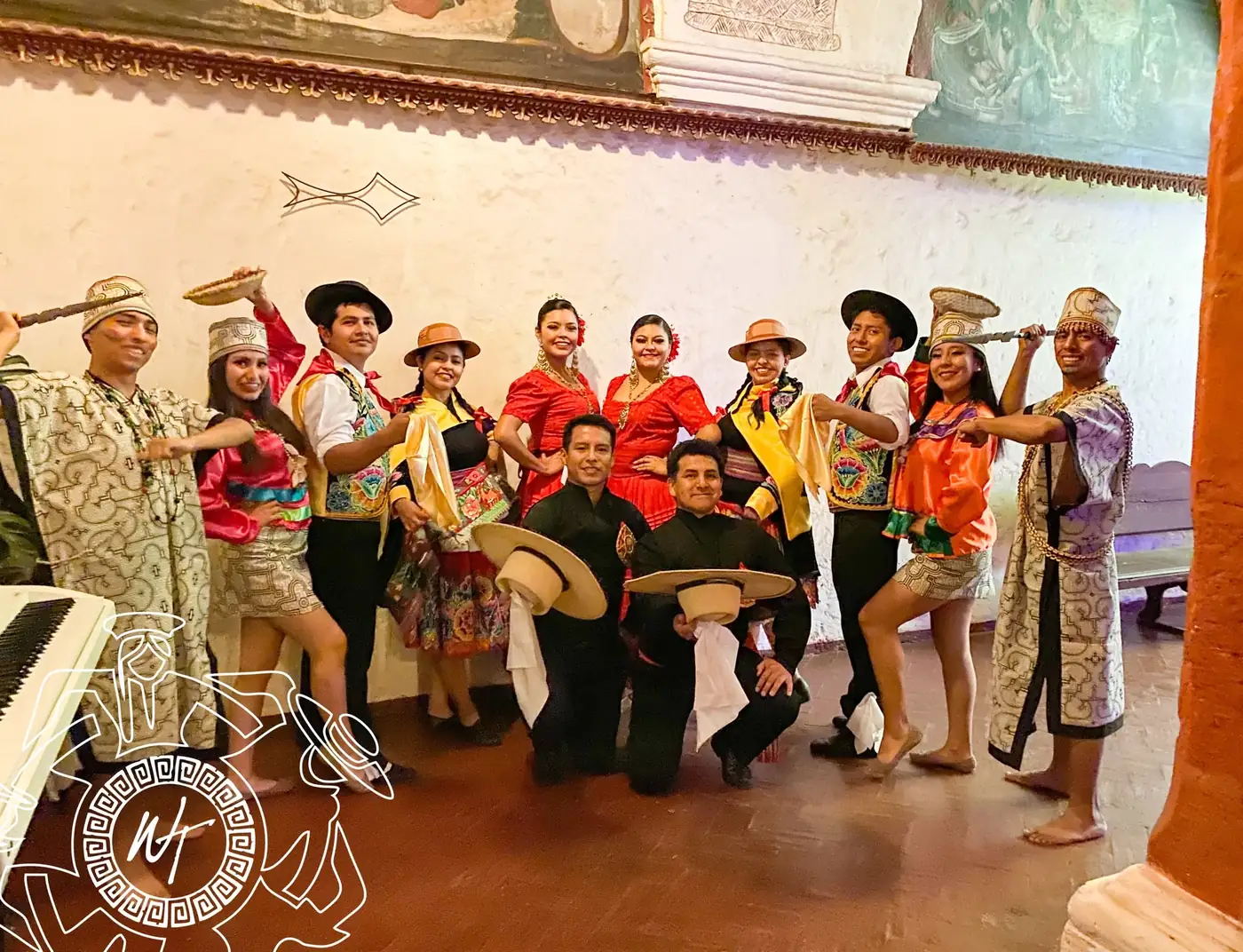 Elenco con instrumentos y sombreros posando en una sala colonial