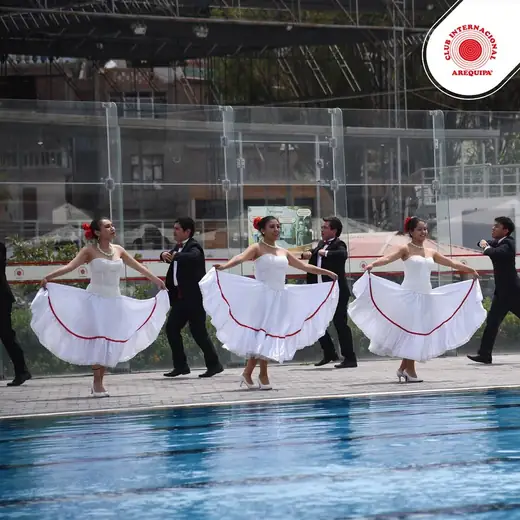 Bailarinas con vestidos blancos de falda amplia junto a una piscina