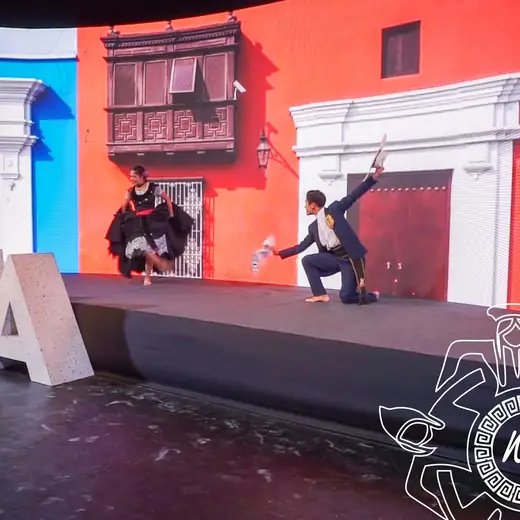 Pareja bailando en un escenario con un balcón colonial de fondo
