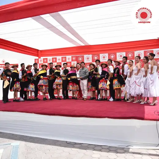 Elenco y autoridades sobre un escenario con toldo rojo